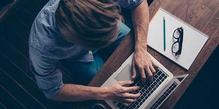 a person working on their laptop, also have a notepad on table Authorizations in SAP S/4HANA and SAP Fiori - Organization