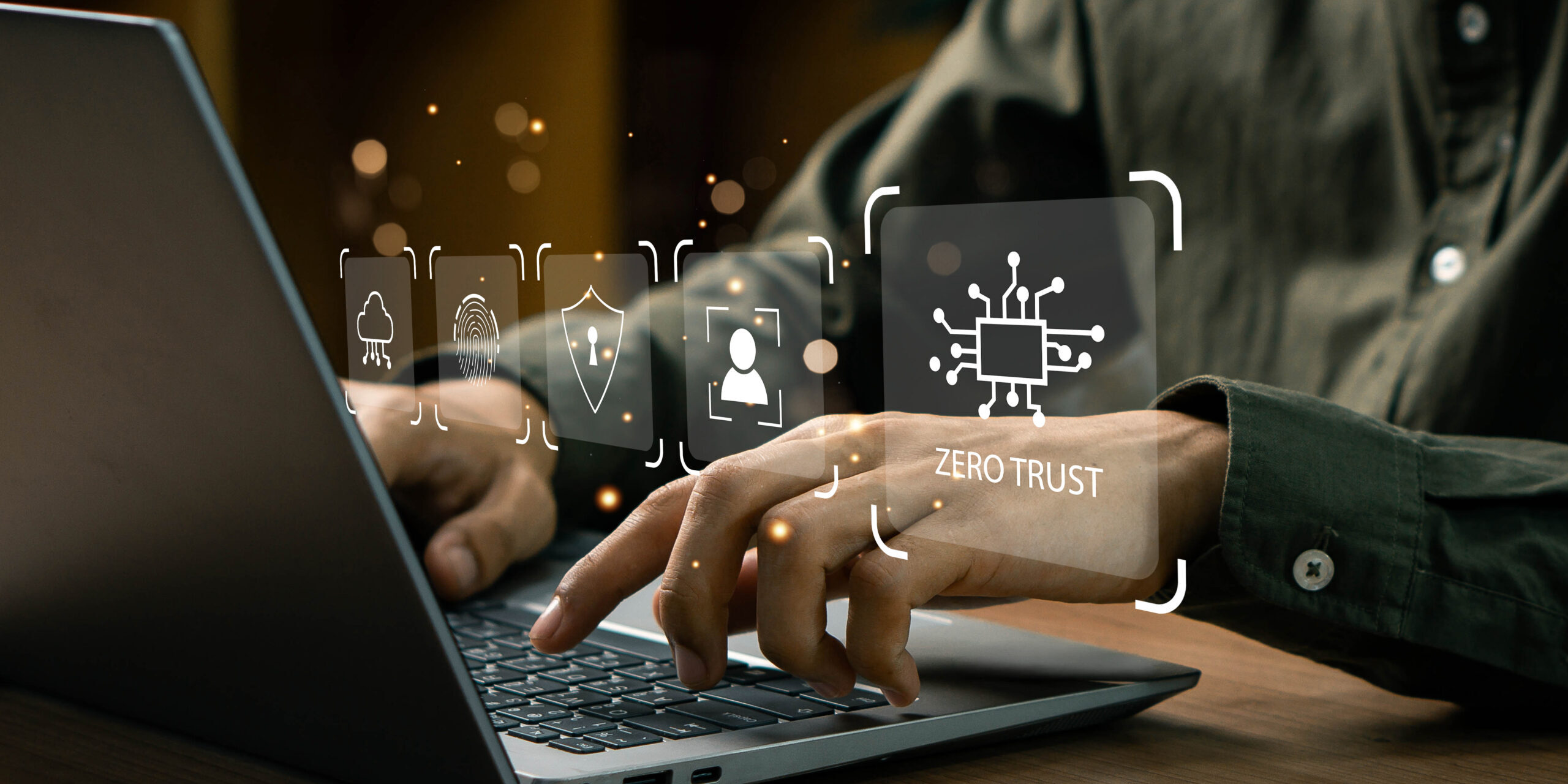Zero Trust Architecture for Enhanced Cybersecurity Hands typing on a laptop keyboard with digital icons overlayed, representing Zero Trust Architecture concepts like security and identity verification.