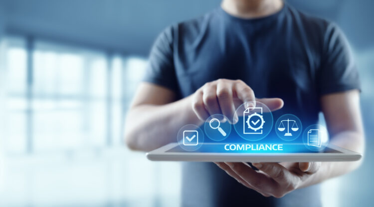 Person using a tablet with virtual compliance icons, illustrating mobile device policy enforcement and security management.