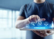Person using a tablet with virtual compliance icons, illustrating mobile device policy enforcement and security management.