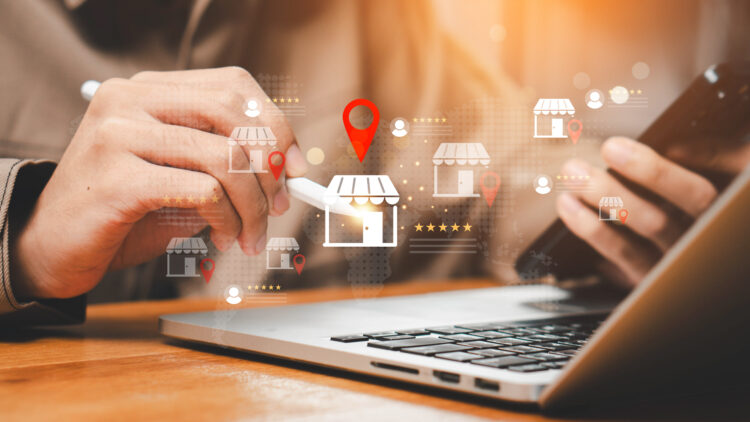 Business professional using a smartphone and laptop with digital location icons representing local businesses and the importance of local IT support for faster response times.