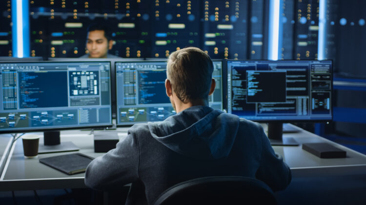 IT professional monitoring multiple screens in a server room to prevent cyber threats and reduce cybersecurity mistakes in a business environment