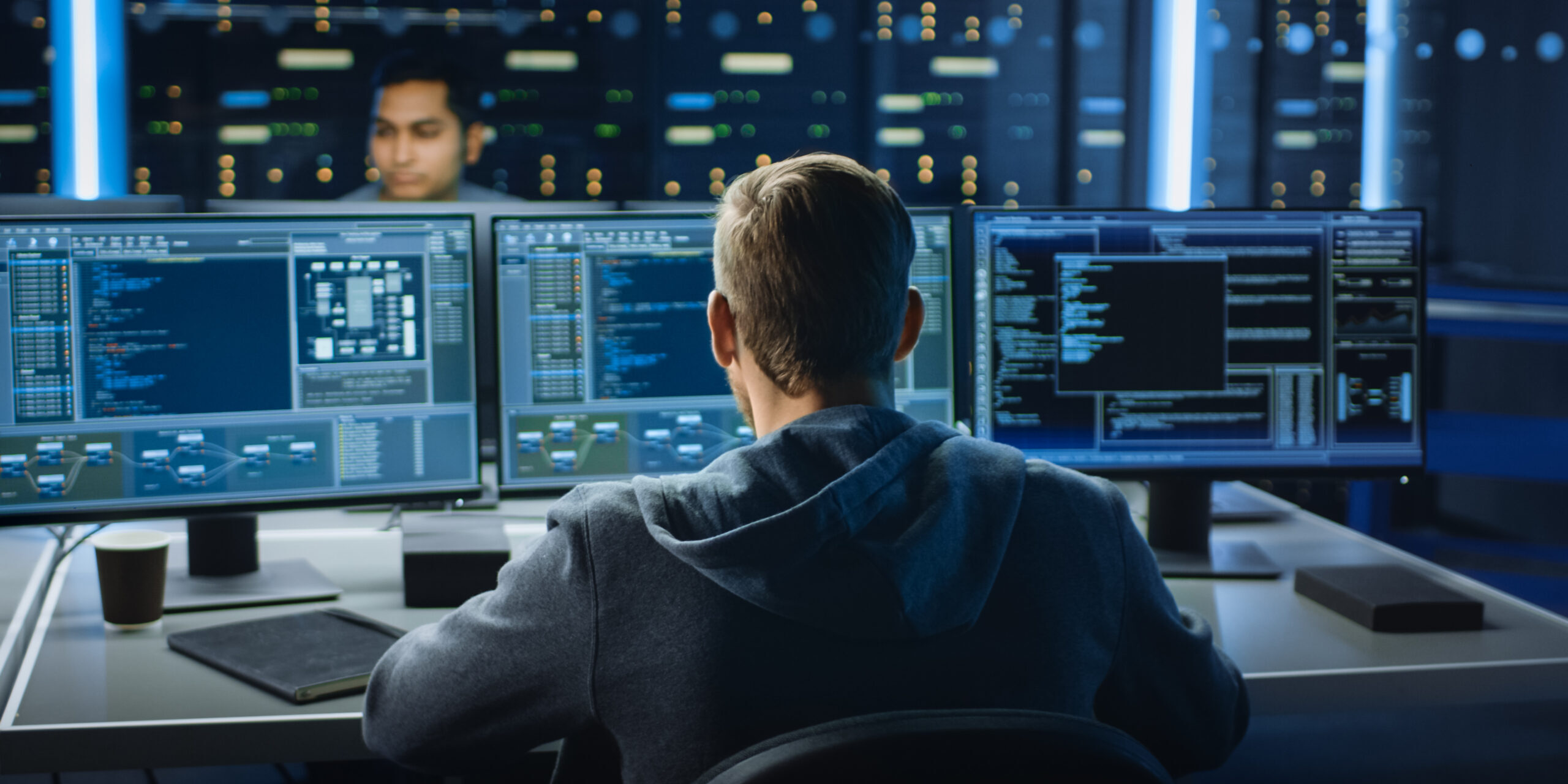 Monitoring Systems to Prevent Cybersecurity Mistakes in Small Businesses IT professional monitoring multiple screens in a server room to prevent cyber threats and reduce cybersecurity mistakes in a business environment