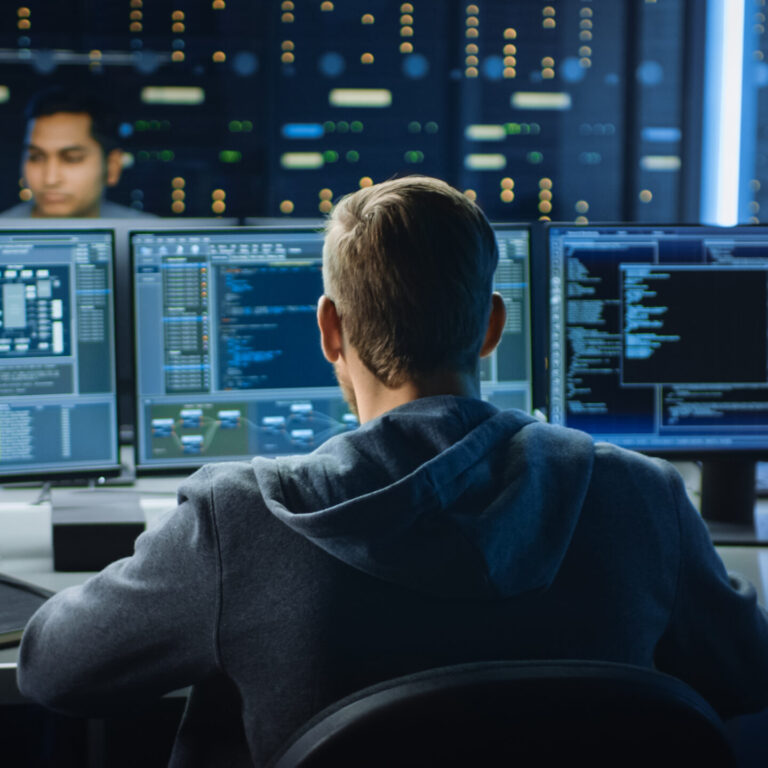 IT professional monitoring multiple screens in a server room to prevent cyber threats and reduce cybersecurity mistakes in a business environment