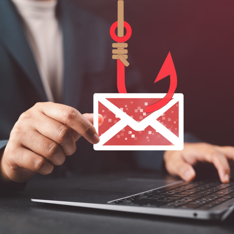How to Stop Someone From Spoofing Your Domain Business professional holding a phishing email icon over a laptop, illustrating email spoofing attacks and domain protection through email authentication protocols.