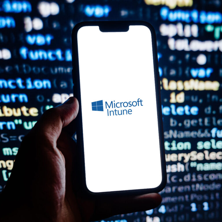 Microsoft Intune Helps Businesses Secure and Manage Devices A smartphone displaying the Microsoft Intune logo against a blurred background of computer code, representing cloud-based endpoint management, mobile device security, and Microsoft 365 device administration.